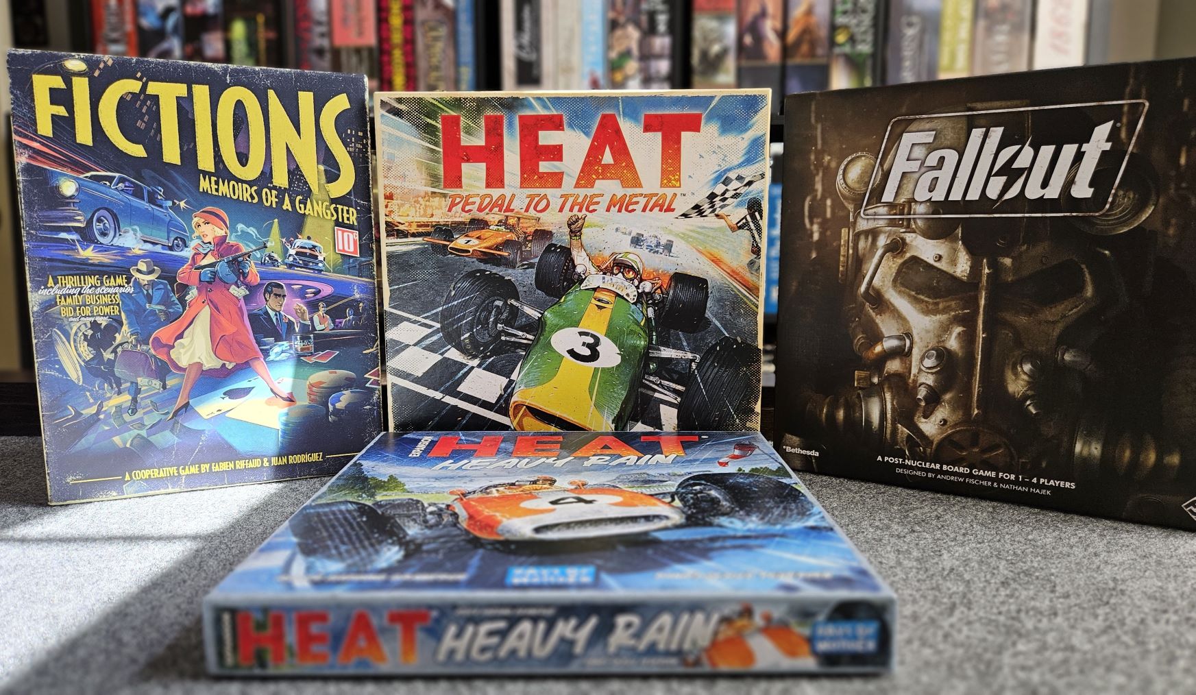 The board games, Fictions: Memoirs of a Gangster, Fallout, Heat: Pedal to the Metal, and Heat: Heavy Rain in front of my board game shelf.